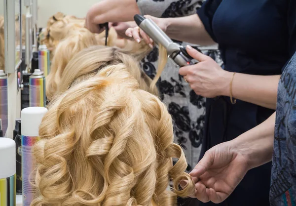 Curling strands of hair on a Curling iron.