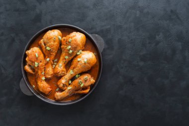 Bir dökme demir tavada köri ile kızarmış tavuk budu.