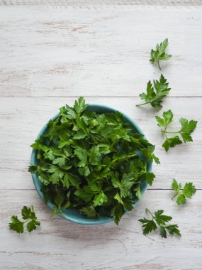 Maydanoz düz lay bırakır. Taze maydanoz Beyaz ahşap bir masa üzerinde bir tabakta. Üstten Görünüm.