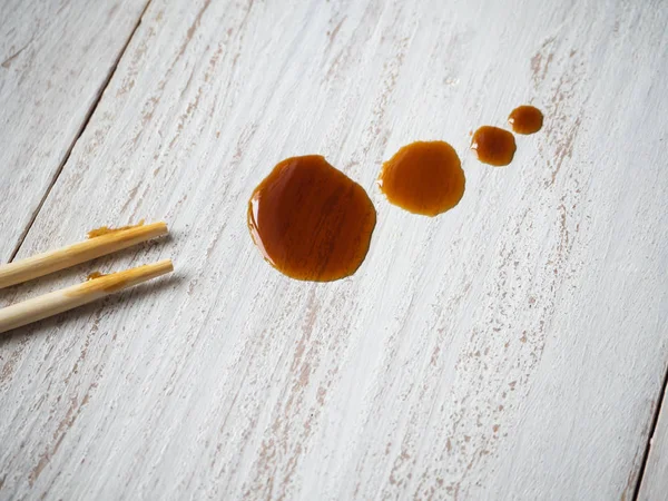 Pałeczki z wycieku sos sojowy na drewnianym stole — Zdjęcie stockowe