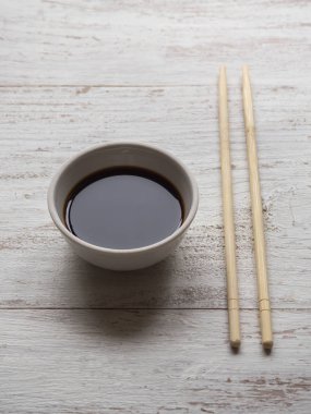 Yemek çubukları ve beyaz tahta masada soya sosu.