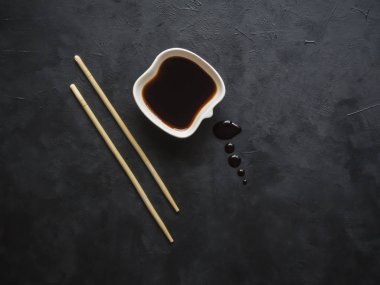 Yemek çubukları ve siyah arka plan üzerine soya sosu.