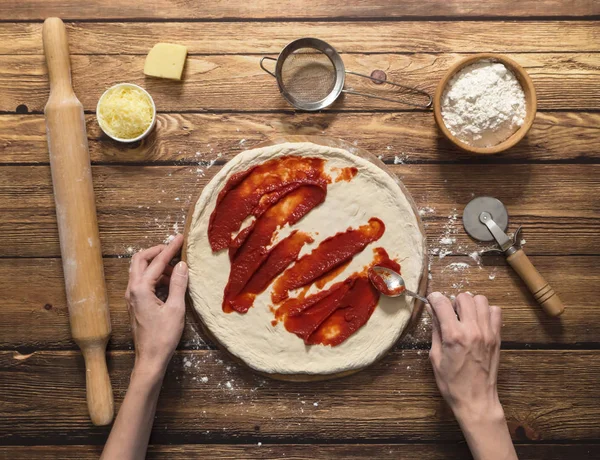 Matlagning pizza. Tomatsås på en raw pizzadeg. — Stockfoto