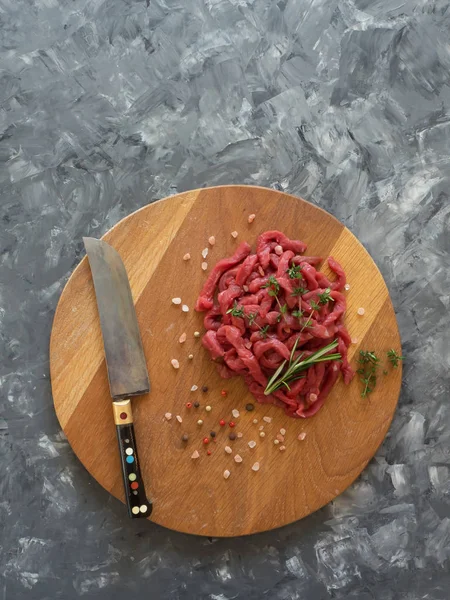 Fresh meat cut into thin strips on cutting board.