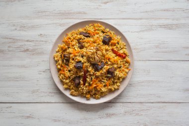 Beyaz ahşap bir masa bir tabağa Özbek pilavı. 