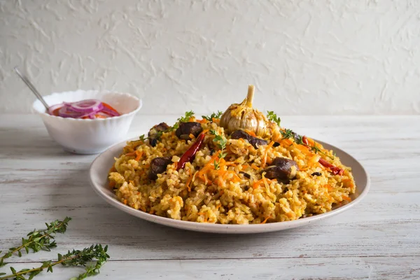 Uzbek pilaf in a plate on a white wooden table. — Stock Photo, Image