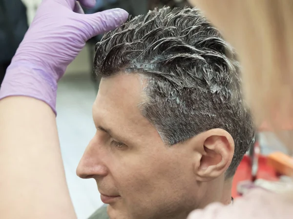 Un hombre se tiñe el pelo en el salón de belleza. . — Foto de Stock