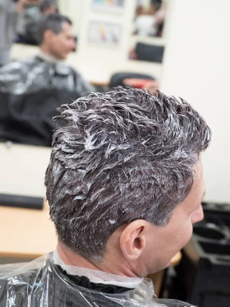 Tonificando el pelo gris en la cabeza del hombre en el salón de belleza — Foto de Stock