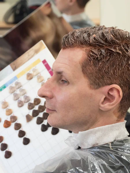 Un hombre elige un tinte para el cabello. Colorante de pelo gris . — Foto de Stock