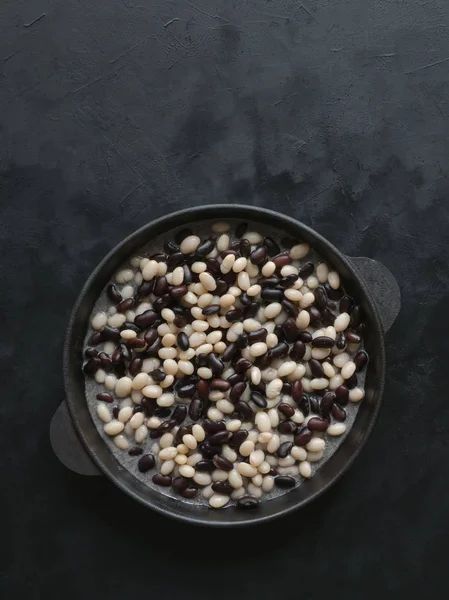 Black and white stewed beans in a pan on the black