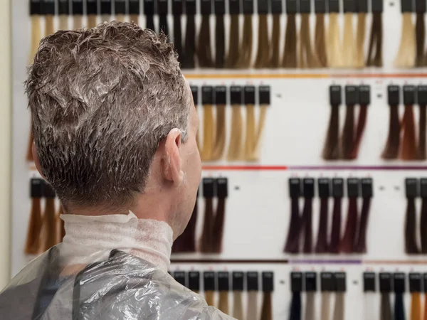 Man chooses paint to dye his hair. Man toning hair
