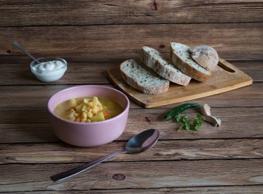 Ahşap bir masa üzerinde bir kase bezelye çorbası. Rustik gıda.