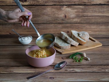 Bir kepçe ile bir el bezelye çorbası dökülen. Rustik gıda