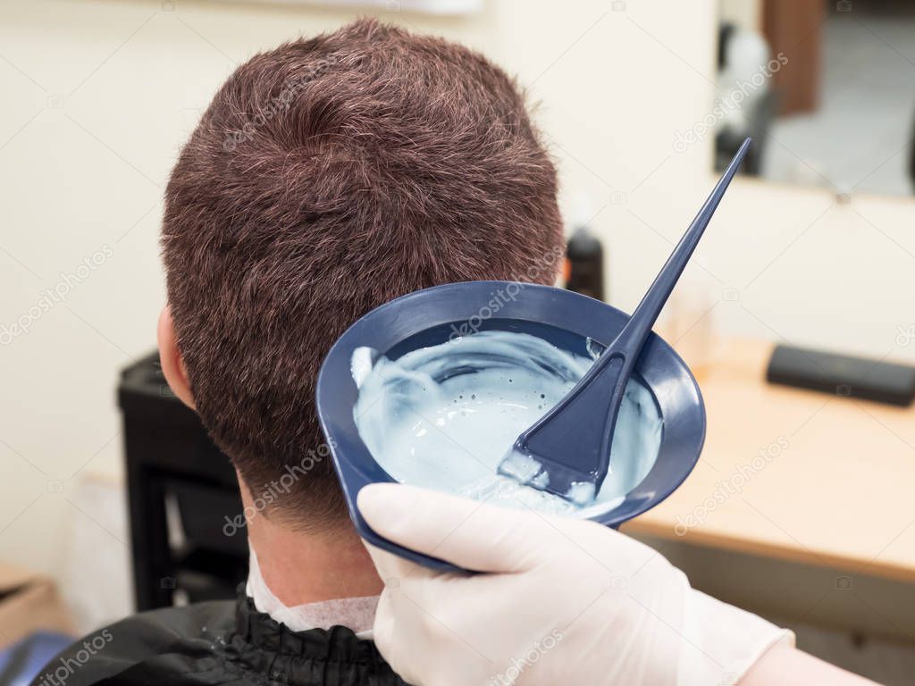 Toning gray hair on the mans head in beauty salon