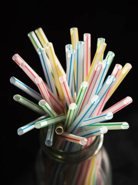 Siyah bir masa üzerinde renkli plastik içme pipetleri 