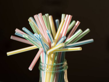 Siyah bir masa üzerinde renkli plastik içme pipetleri 