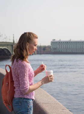 Woman with a drink in a paper cup in hand.