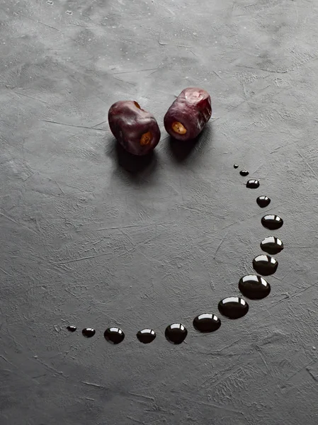 Black Ramadan background with dates and dates syrup poured in the shape of crescent moon