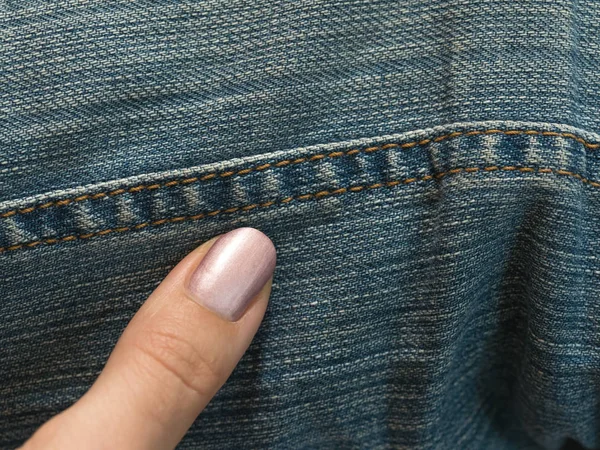 Palec wskazuje na szew dżinsy. — Zdjęcie stockowe