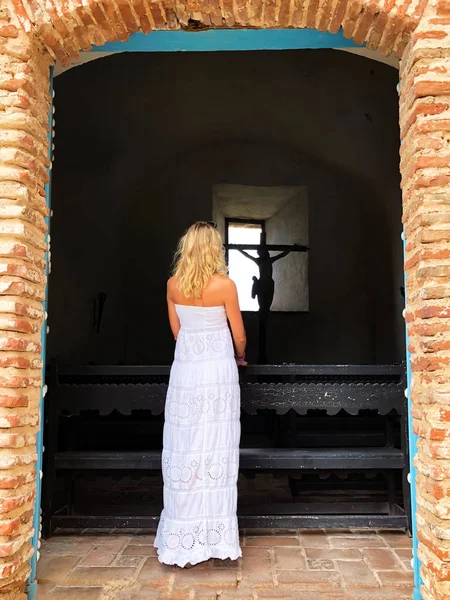 Schönes blondes Mädchen in der Nähe eines Jesuskreuzes. — Stockfoto