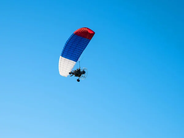 Kleurrijke aangedreven paraglider tegen de blauwe lucht. — Stockfoto