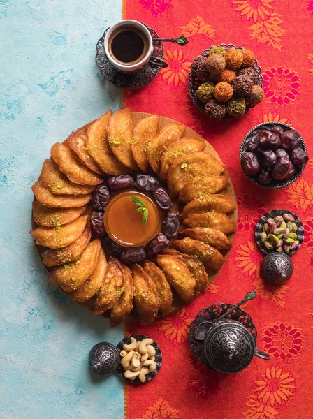 Arabic sweets. Arabian Qatayef pancake stuffed with sweet cheese and nuts on the blue table.