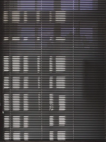 Dark blinds close the sunny window. Dark window background