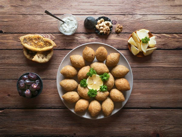 Köstliche gebratene Kibbeh mit Joghurtsoße in einer Schüssel auf einem Teller auf einem alten Holztisch serviert. klassisches libanesisches Rezept — Stockfoto