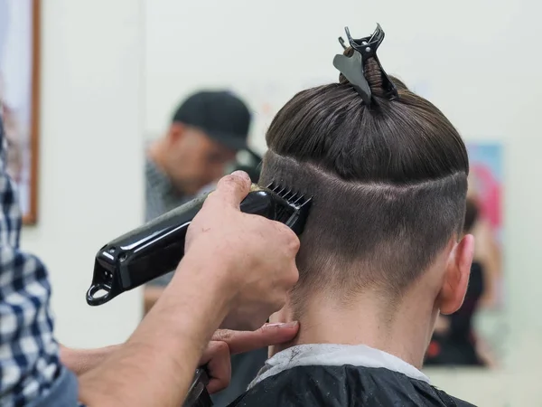Friseur mit Haarschneidemaschine arbeitet an Haarschnitt des bärtigen Typen Barbershop Hintergrund — Stockfoto