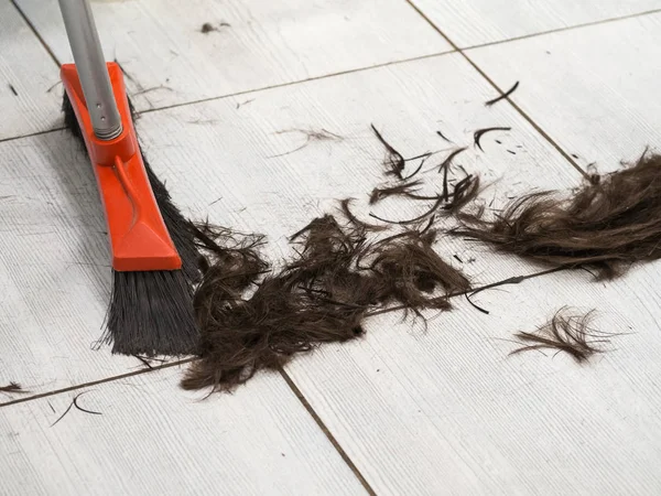 Peluquería barrer recortes de cabello en el suelo en la peluquería — Foto de Stock