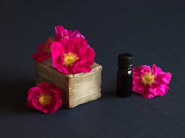 Jabón hecho a mano y flores de rosas en una mesa negra — Foto de Stock