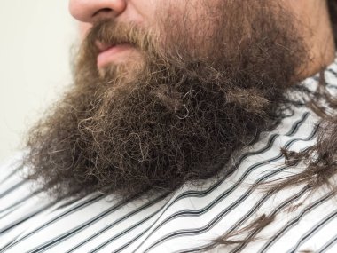 Sakallı iri bir adam sakalını keser..