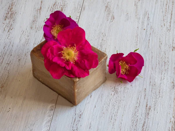 Ručně vyráběné mýdlo a růže na dřevěném stole — Stock fotografie