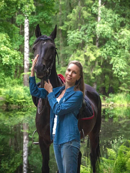 Menina bonita sorrir para seu cavalo. Retrato ao ar livre no parque verde — Fotografia de Stock