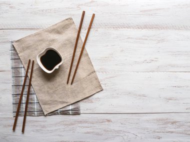 Beyaz ahşap masada soya sosu ve çubuklar 