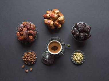 Lezzetli tarihler ve siyah masada kakule ile Arap kahve fincanı. Üstte görüntü