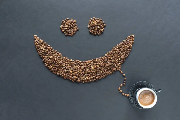 Sorriso de grãos de café com xícara de café no fundo preto — Fotografia de Stock