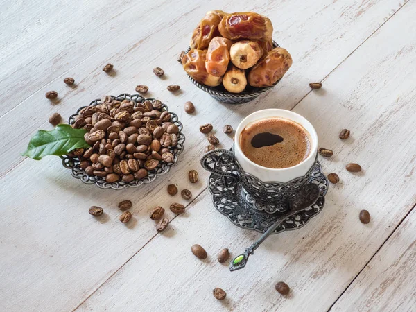 Tasse Kaffee, Kaffeebohnen und frische Datteln auf weißem Holzgrund — Stockfoto