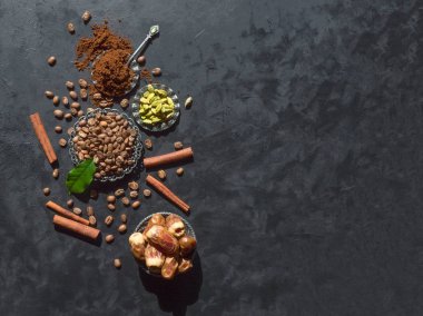 Kahve çekirdekleri, zemin tozu, hurma meyve, tarçın ve siyah arka plan üzerinde kakule. Kopyalama alanı ile üstte görünüm