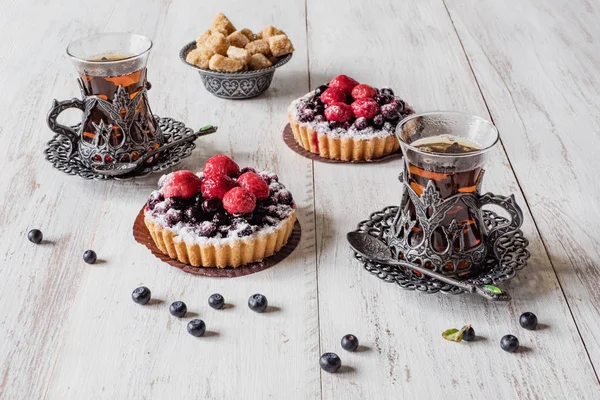 Tea cups and tarts cakes sweets with berries — Stock Photo, Image