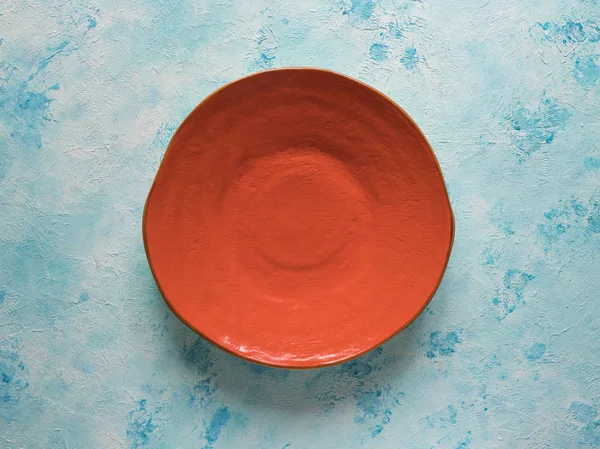 青い背景に手作りのオレンジセラミックプレート — ストック写真