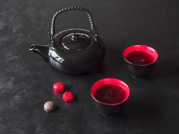 Schwarze Teekanne mit chinesischem Tee und zwei Tassen auf dem schwarzen Tisch — Stockfoto