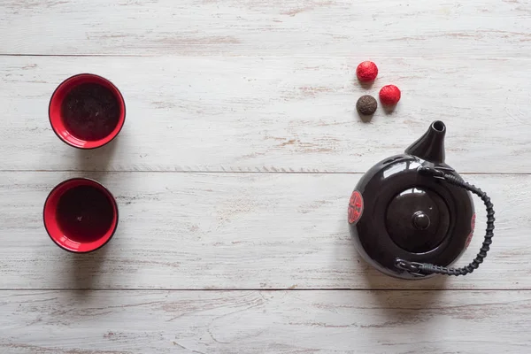 Rote Tassen Tee und schwarze Teekanne auf dem Holztisch — Stockfoto