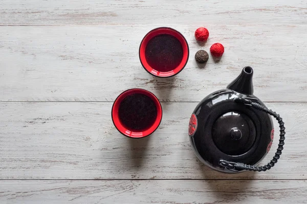 Rote Tassen Tee und schwarze Teekanne auf dem Holztisch — Stockfoto