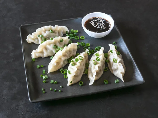 Knödel mit Sojasauce auf schwarzem quadratischen Teller — Stockfoto