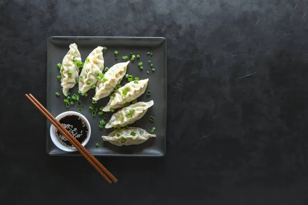 Dumplings con salsa de soja en plato cuadrado negro —  Fotos de Stock