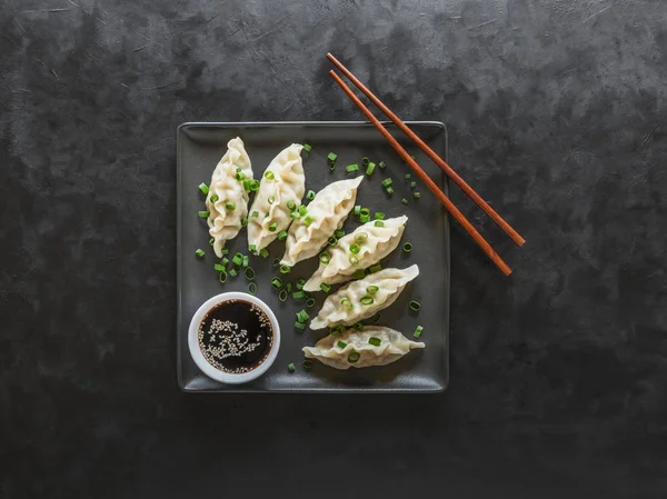 Dumplings con salsa de soja en plato cuadrado negro —  Fotos de Stock