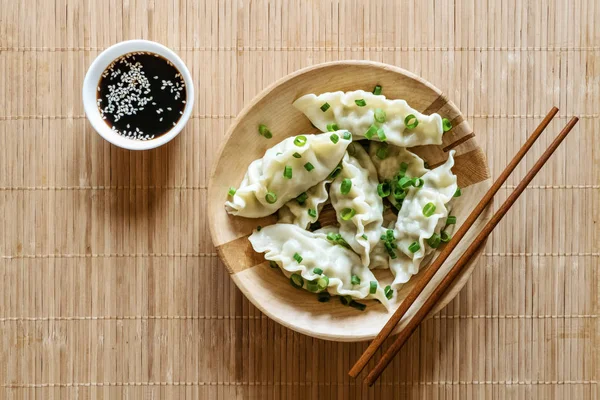 Bolinhos asiáticos em tigela, pauzinhos, fundo de madeira rústica. Bolinhos chineses para jantar — Fotografia de Stock