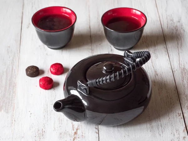 Two red cups tea and black teapot on the white wooden table — Stock Photo, Image