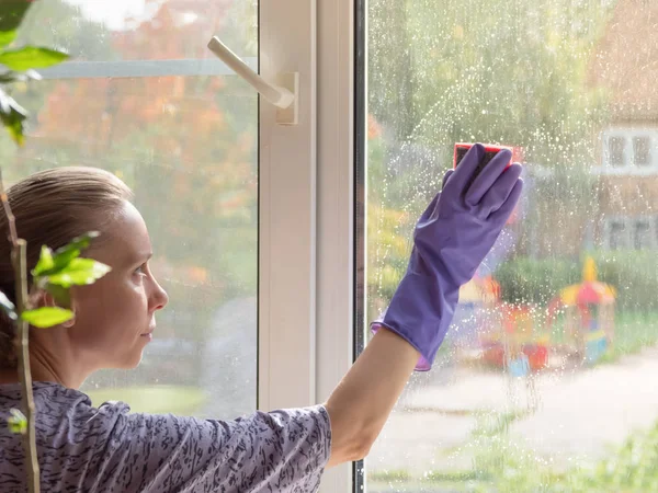 Woman washes the window with a sponge. Close up.